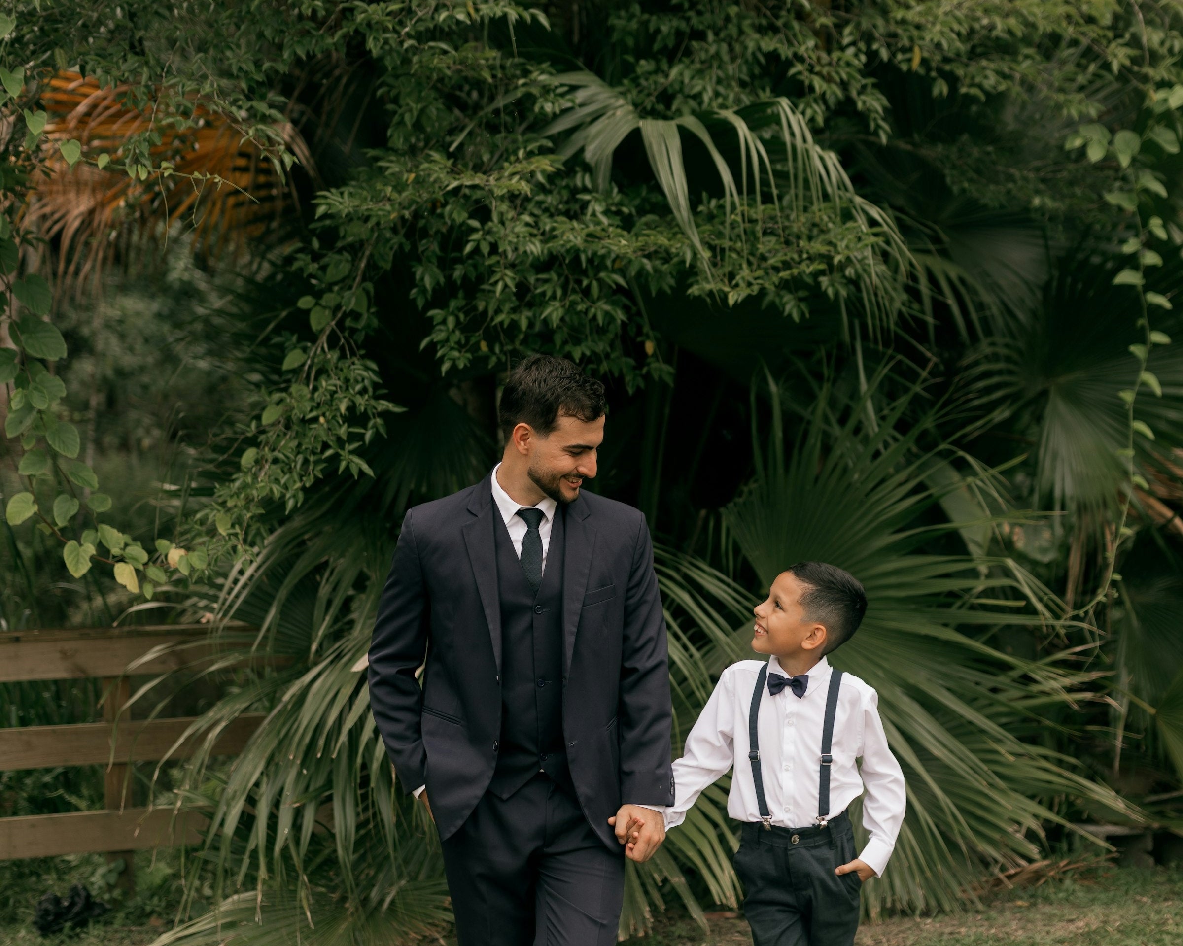 Father and son in matching suits holding hands