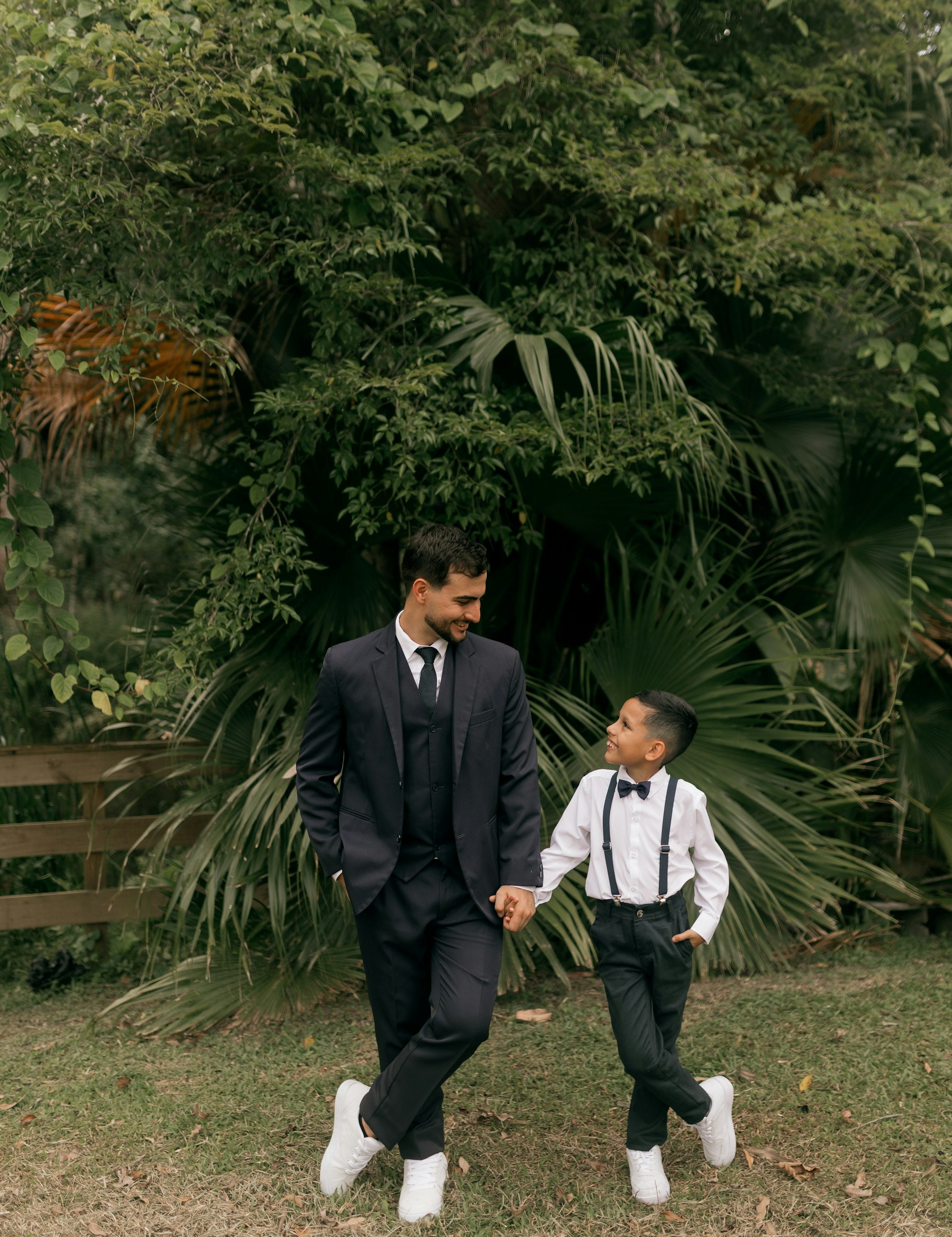 Father and son in matching suits holding hands