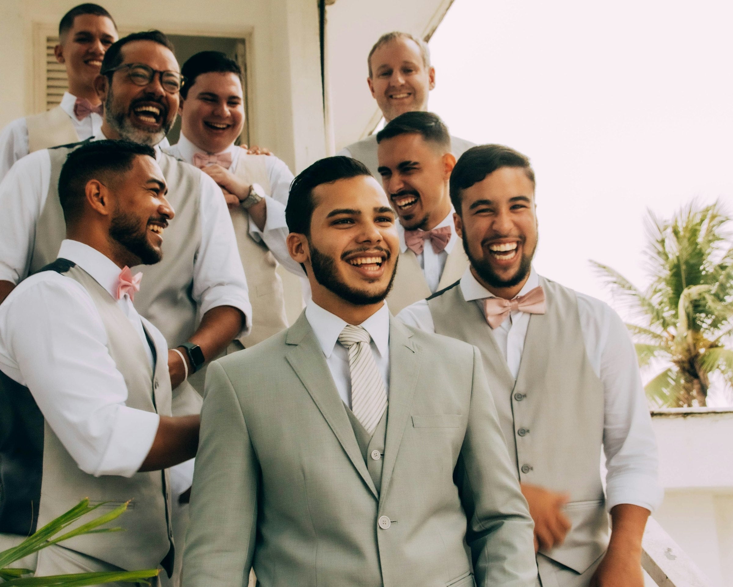Groom and groomsmen smiling together at a wedding