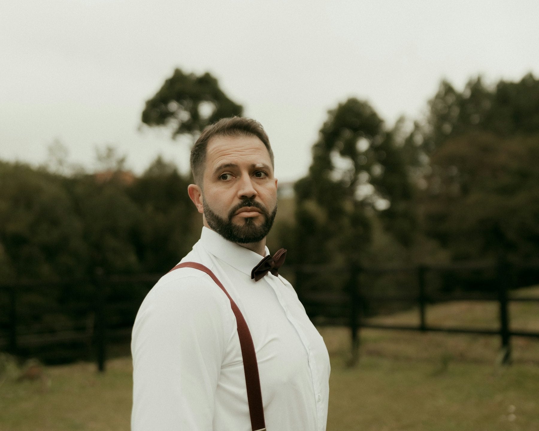 Man wearing a white shirt, bow tie and suspenders outdoors