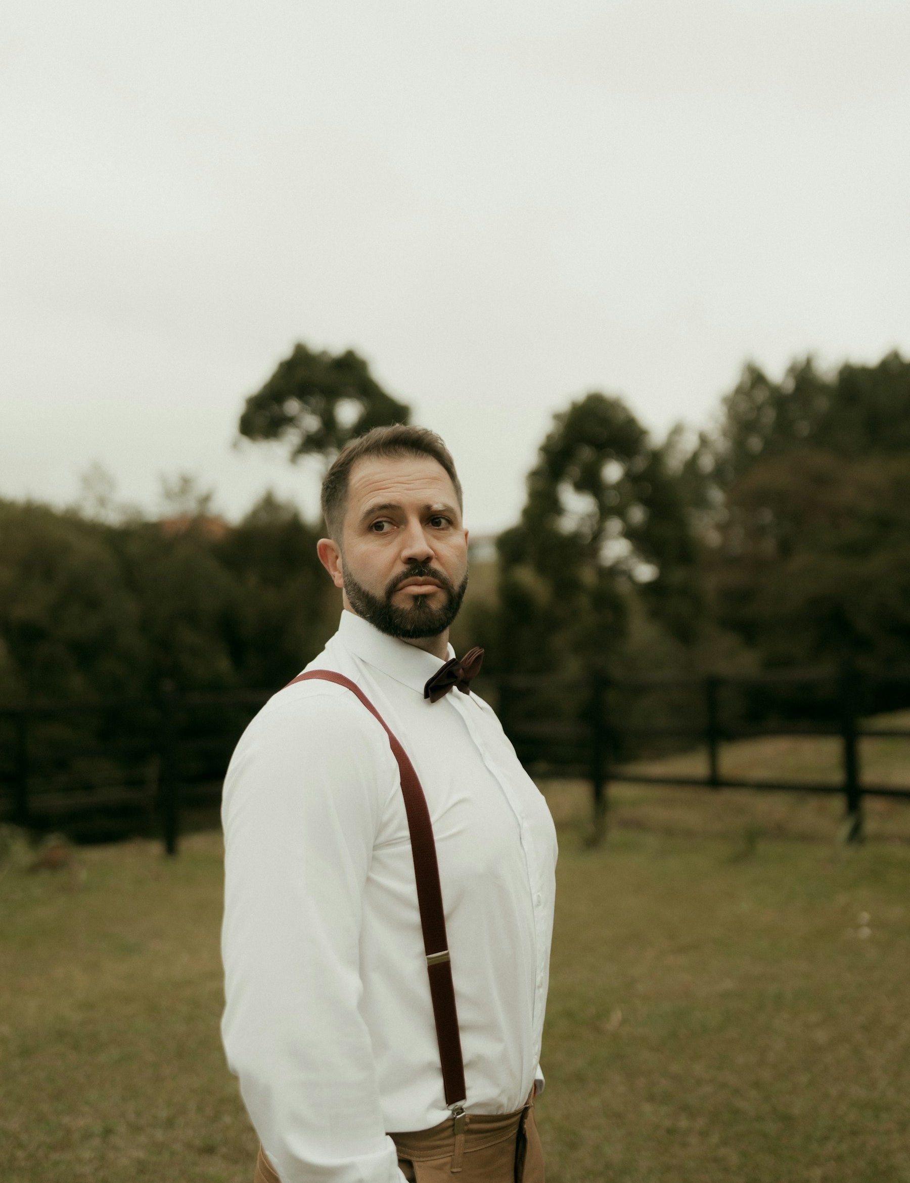Man wearing a white shirt, bow tie and suspenders outdoors