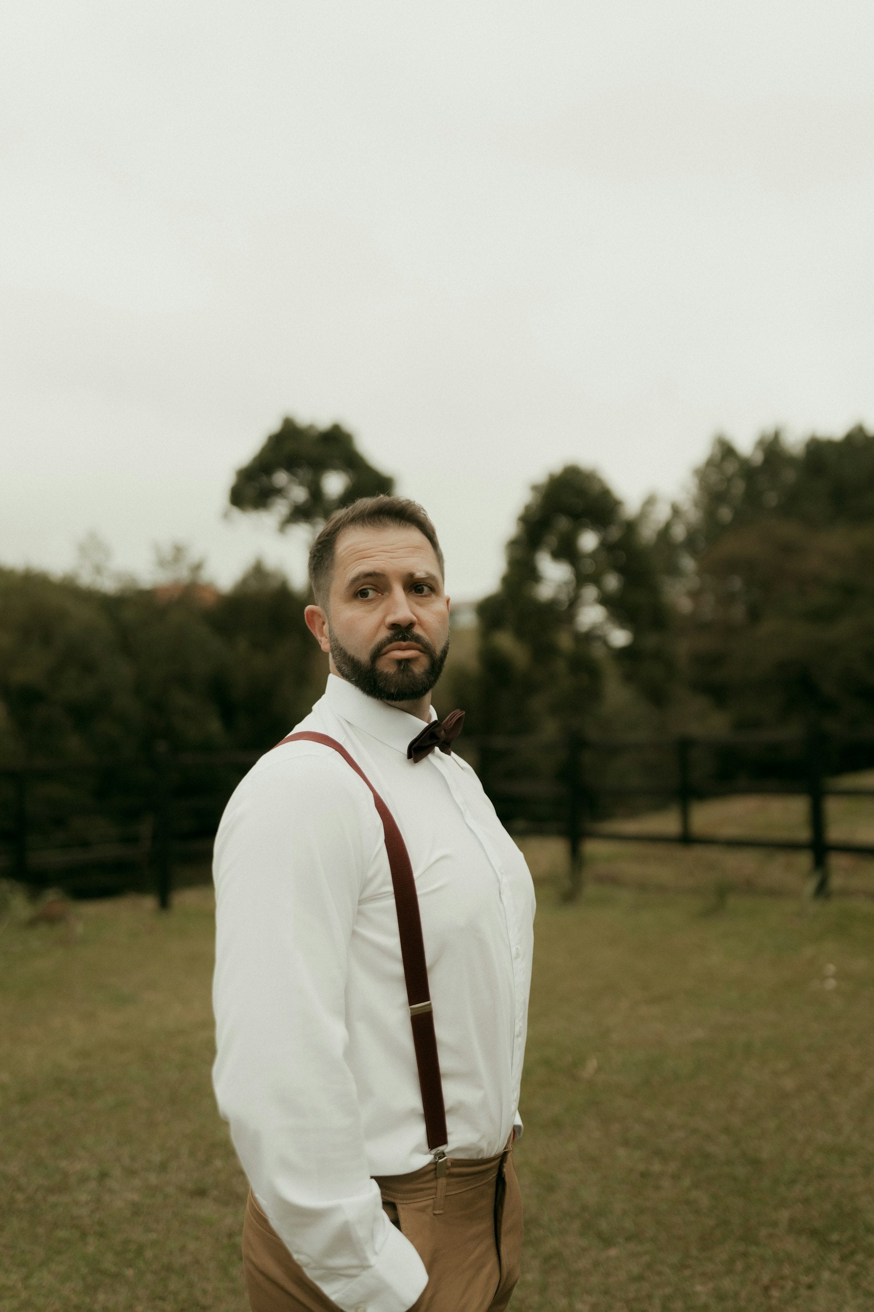 Man wearing a white shirt, bow tie and suspenders outdoors