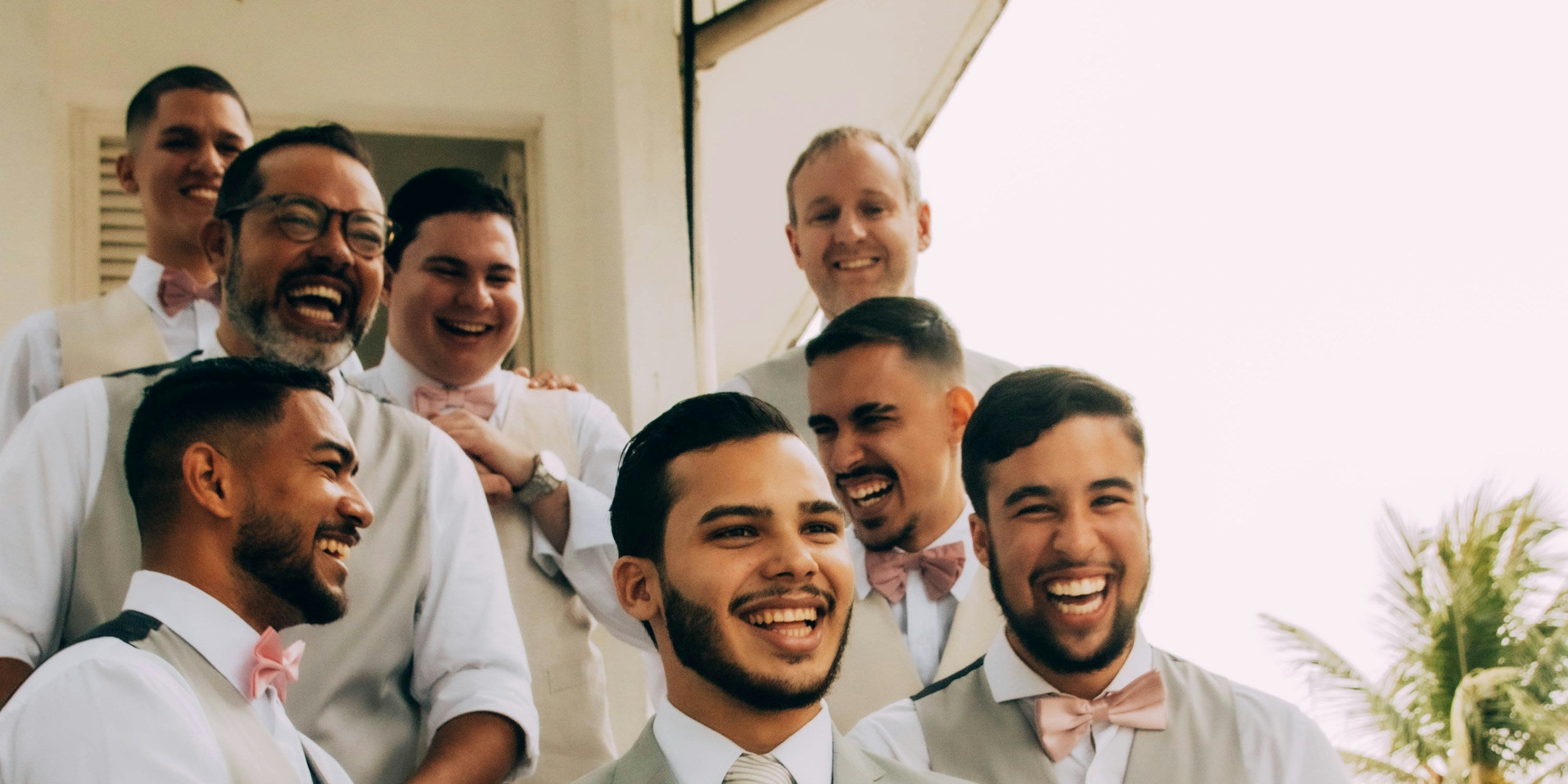 Groom and groomsmen smiling together at a wedding