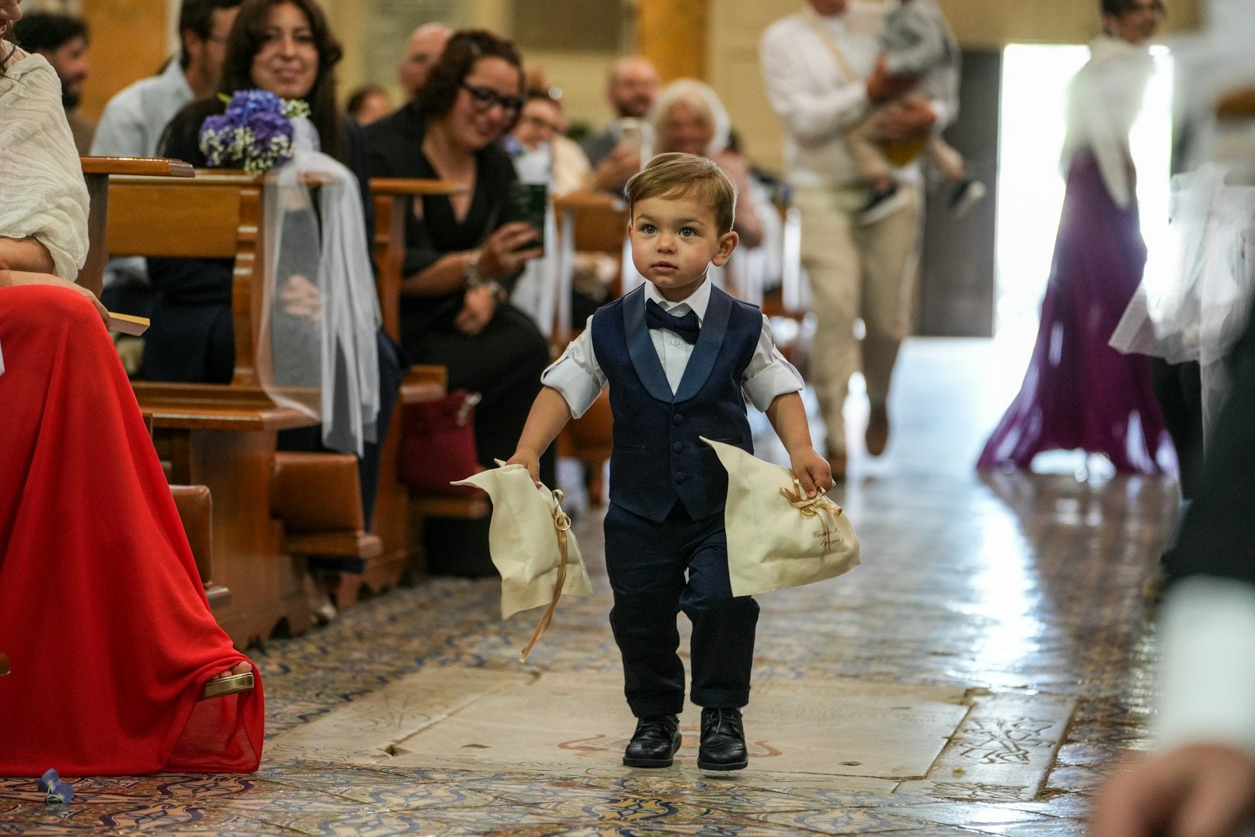 Young ring bearer in a suit walking down the wedding aisle
